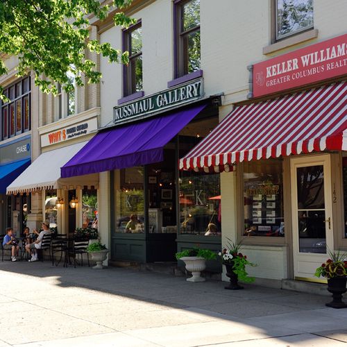 People dining under red umbrellas on a downtown Granville sidewalk